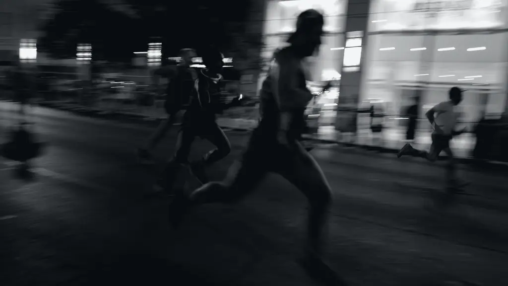 Corredores em movimento durante uma prova noturna, registrados com rastro de velocidade.