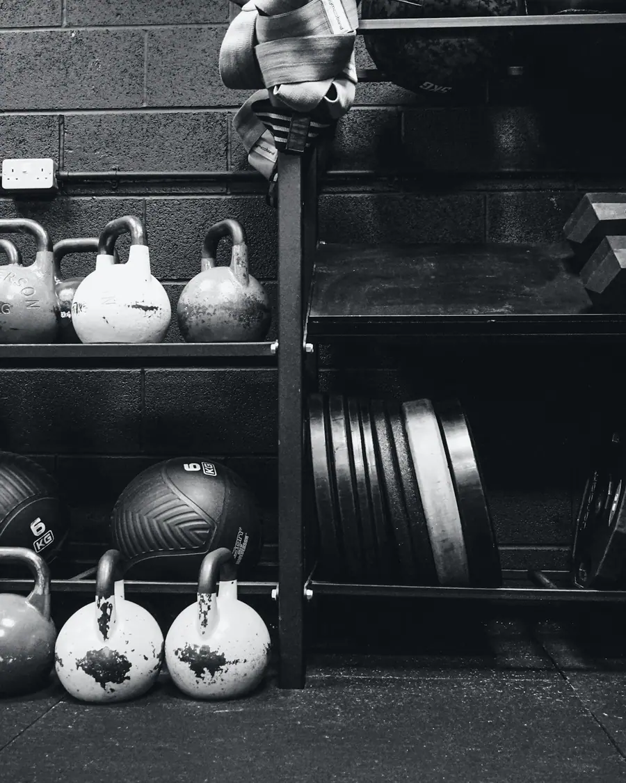 Imagem ilustrativa: estante com kettlebells e anilhas em um centro de treinamento.